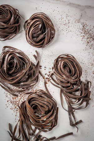Raw unprepared chocolate pasta noodles. On a white kitchen marble table. Copy space top viewの写真素材