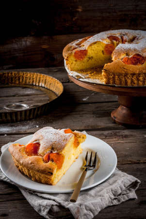 Homemade autumn and summer baked pastries. Sponge cake with apricots. Cut into pieces, plate, fork. On the stand. On the old wooden rustic table. Copy spaceの写真素材