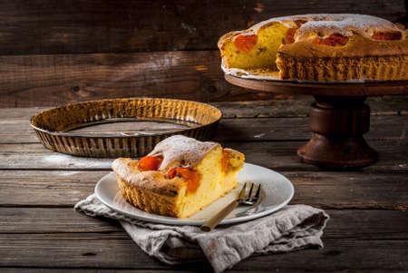 Homemade autumn and summer baked pastries. Sponge cake with apricots. Cut into pieces, plate, fork. On the stand. On the old wooden rustic table. Copy spaceの写真素材