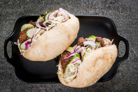 Sandwiches. Fast food. Traditional Chinese Asian bao buns with meat stuffing (pork, beef), fresh vegetables and hot sauce. On a dark stone table. Copy space top viewの写真素材