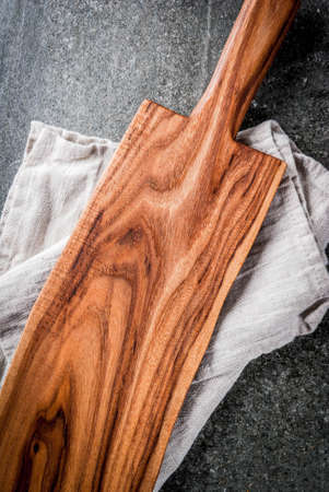 Cooking background, Old wooden cutting board with kitchen towel on black stone table. Top view, copy spaceの写真素材