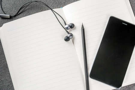 Office, black desktop with appliances. Background. Notepad, pens (pencils), smartphone and...
