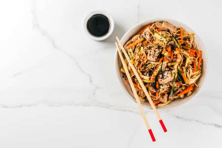 Traditional Asian food. Lunch stirfry: rice noodles, zucchini, carrots, bamboo, mushrooms, pork...