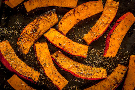 Traditional autumn dishes from pumpkin. Fried baked on grill pumpkin with spices, olive oil, herbs. On a baking sheet, on a rustic wooden old table. Top viewの写真素材