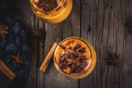 Traditional autumn dishes, spicy pumpkin pie smoothie with cinnamon, anise and oatmeal. In portioned glasses, on rustic wooden old table. Copy space top viewの写真素材
