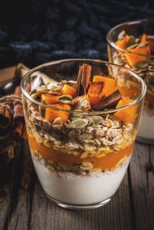 Traditional autumn dishes, spicy pumpkin pie overnight oatmeal with cinnamon, anise and maple syrup. In portioned glasses, on wooden old rustic table. Copy spaceの写真素材