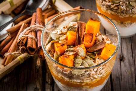 Traditional autumn dishes, spicy pumpkin pie overnight oatmeal with cinnamon, anise and maple syrup. In portioned glasses, on wooden old rustic table. Copy spaceの写真素材