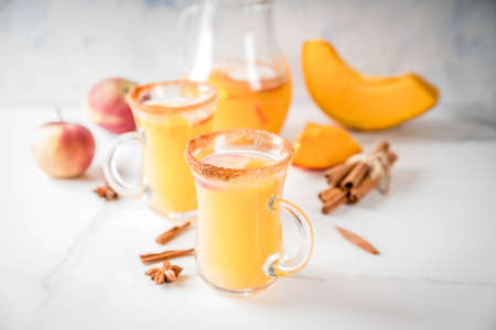 Halloween, Thanksgiving. Traditional autumn, winter drinks and cocktails. Spicy hot pumpkin sangria, with apple, cinnamon, anise. On a white marble table, in glass mugs. Selective focus, copy spaceの写真素材