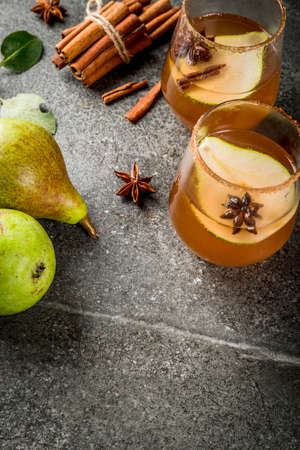 Autumn drinks. Mulled wine. Traditional autumn spicy cocktail with pear, cider and chocolate syrup, with cinnamon, anise, brown sugar. On black stone table. Copy spaceの写真素材