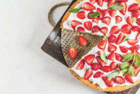 Homemade biscuit cake with whipped cream, fresh organic raw strawberries and mint. On a white stone table. Copy space top viewの写真素材