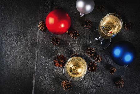 Dry Champagne in glasses, Christmas colorful balls, pine cones, New Year still life composition on dark stone background, selective focus copy spaceの写真素材