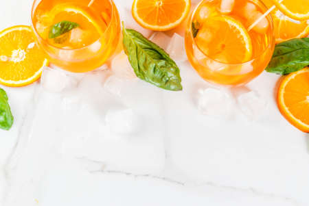 Summer refreshing drink, lemonade, cocktail with orange and basil. On a white marble table, copy space top viewの写真素材