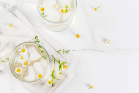 Summer refreshing drinks, infused herbal water, iced tea. Chamomile Honey and Whiskey Cocktail with thyme in glasses, on a white marble table. Copy space top viewの写真素材