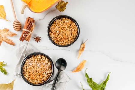 Dietary autumn pastries, breakfast. Crumble pumpkin pie, maple syrup and oatmeal flakes, in plate saucers, on a white marble table. Copy spaceの写真素材