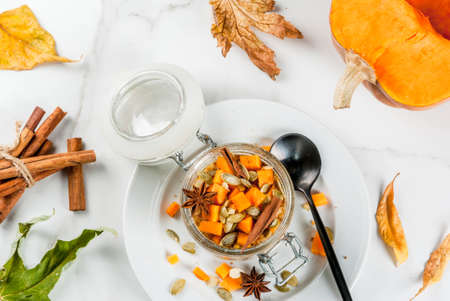 Healthy vegan food. Dietary breakfast or snack. Pumpkin pie overnight oats, with  pumpkin, yogurt, cinnamon, spices. In a glass, on a white marble table. Copy space top viewの写真素材