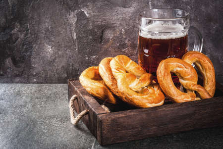 Selection of traditional German food Oktoberfest. Beer, baked pork shank, popcorn, assortment of different sausages, homemade bretzels. On a black stone background copy spaceの写真素材