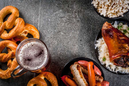 Selection of traditional German food Oktoberfest. Beer, baked pork shank, popcorn, assortment of different sausages, homemade bretzels. On a black stone background copy space top viweの写真素材