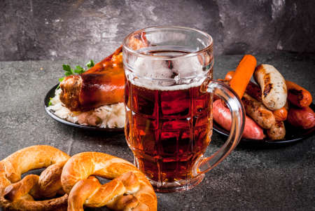 Selection of traditional German food Oktoberfest. Beer, baked pork shank, popcorn, assortment of different sausages, homemade bretzels. On a black stone background copy spaceの写真素材