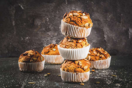 Autumn and winter baked pastries. Healthy pumpkin muffins with traditional fall spices, pumpkin seeds. Black stone table, copy spaceの写真素材