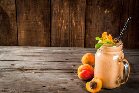 Homemade organic smoothie from yogurt and apricot. In Mason Jar, on a rustic old wooden table, with apricots and mint leaves. Copy spaceの写真素材