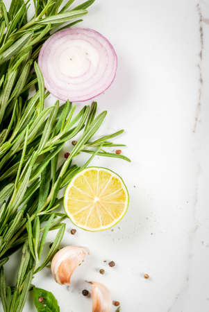 Food cooking background, white marble kitchen table. Spices and herbs for cooking dinner - rosemary, lime, salt, pepper, garlic, onion. Copy space top viewの写真素材
