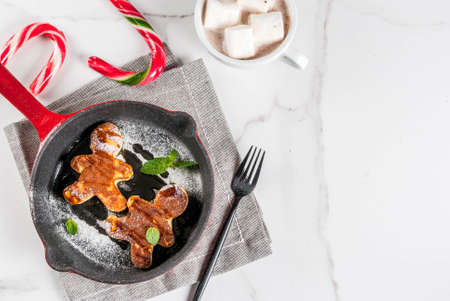 Funny food for Christmas. Kids breakfast pancake decorated like gingerbread men, with hot chocolate...
