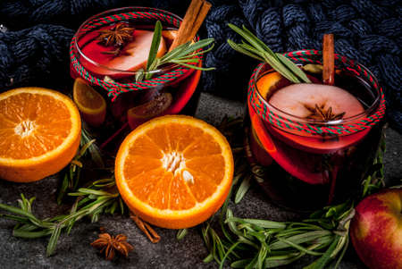 Traditional winter and autumn drinks. Christmas and Thanksgiving Cocktails. Mulled wine with orange, apple, rosemary, cinnamon and spices on a dark stone background, copy spaceの写真素材