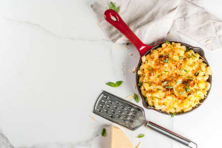 Mac and cheese, american style macaroni pasta with cheesy sauce and crunchy breadcrumbs topping, in portioned pan, white marble table, copy space top viewの写真素材