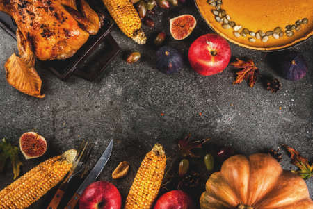 Thanksgiving Day food. Roasted whole chicken or turkey with autumn vegetables and fruits: corn, pumpkin, pumpkin pie, figs, apples, on dark grey background, top view  copy spaceの写真素材