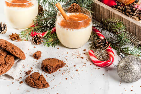 Chocolate Crinkle cookies for Christmas, with eggnog cocktail, candy cane, Christmas tree and holiday decoration, on white marble table, copy spaceの写真素材