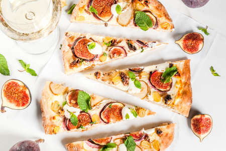 Autumn baking recipes. Sweet pie pizza or fruit focaccia with figs, pears, grapes, cream cheese, walnuts and mint. With white wine glass, on white marble background, copy space top viewの写真素材