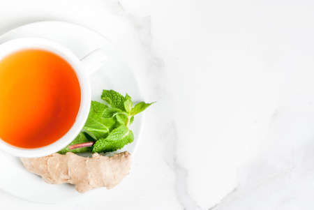 Cup of ginger tea with lemon,fresh mint and honey, on white marble table, copy space top viewの写真素材
