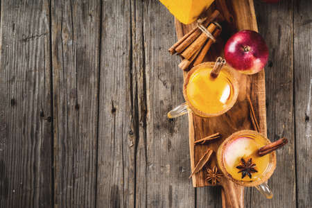 Halloween, Thanksgiving. Traditional autumn, winter drinks and cocktails. Spicy hot pumpkin sangria, with apple, cinnamon, anise. On old rustic wooden table, in glass mugs. Top view copy spaceの写真素材