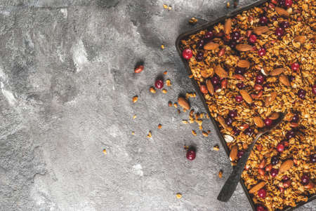 Ideas for a winter, autumn breakfast. Thanksgiving, Christmas. Homemade fresh cooked honey granola with nuts (almonds, peanuts, hazelnuts) and cranberries. On gray concrete table, Copy space top viewの写真素材