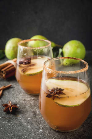 Autumn drinks. Mulled wine. Traditional autumn spicy cocktail with pear, cider and chocolate syrup, with cinnamon, anise, brown sugar. On black stone table. Copy spaceの写真素材
