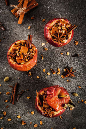 Autumn food recipes. Baked apples stuffed with granola, toffee and spices. On black stone table, copy space top viewの写真素材
