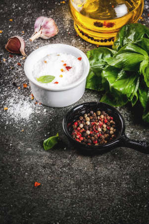 Ingredients for cooking dinner, spices, dark stone table. Basil leaves, olive oil, garlic, salt and pepper, Copy spaceの写真素材