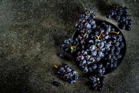 Raw natural organic farmer's black grapes, bunches on black plate, dark stone background, top view...