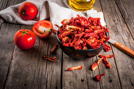 Homemade sun-dried organic tomatoes, crispy tomato chips, on an old rustic wooden table with fresh...