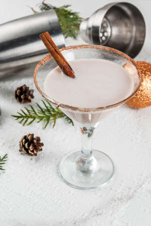 Ideas and recipes for Christmas drink. Eggnog martini, with cinnamon sticks, on white marble table with Christmas decoration, copy spaceの写真素材