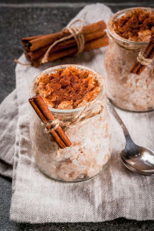 Spanish, South American, Mexican dessert. Sweet porridge, rice pudding. Arroz con leche. In portioned jars, decorated with cinnamon and sugar. On a dark stone table. Copy spaceの写真素材