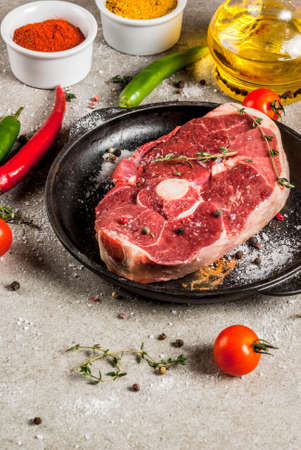 Fresh raw meat. A piece of lamb's tenderloin, with a bone, with a cutting ax, with spices for cooking on grey stone table Copy spaceの写真素材