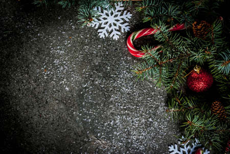 Christmas dark background with christmas tree branches, pine cones, candy cane sweets, gifts, christmas balls and decorations, top view copy spaceの写真素材