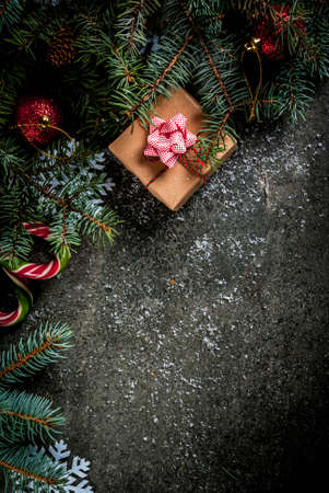 Christmas dark background with christmas tree branches, pine cones, candy cane sweets, gifts, christmas balls and decorations, top view copy spaceの写真素材