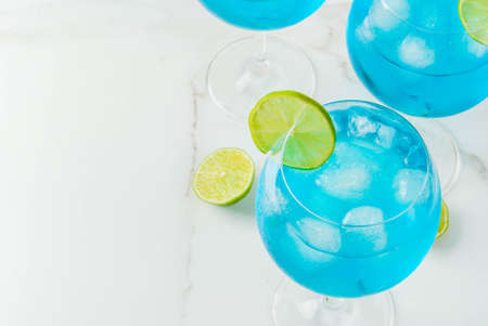 Alcohol drink. Glasses with a blue alcoholic cocktail with ice and lime garnish. Blue Curacao. Liquor. Copy spaceの写真素材