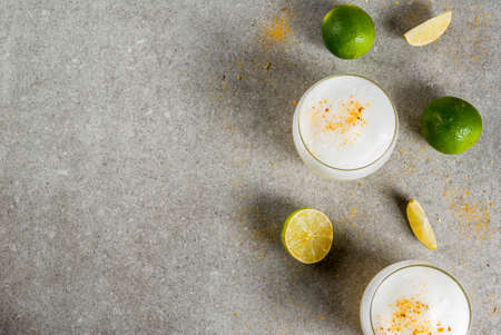 Peruvian, Mexican, Chilean traditional drink pisco sour liqueur, with fresh lime, on gray stone table, copy space top viewの写真素材