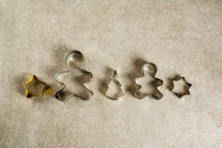 Christmas cookie cutters on gray kitchen stone table - christmas tree, gingerbread man, stars. Top view copy space, christmas baking conceptの写真素材