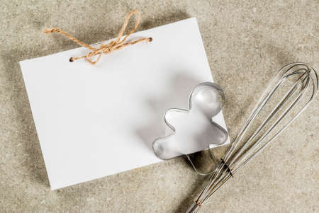 Christmas baking background, notepad for recipes, whisk for whipping, gingerbread man cookie cutter on gray kitchen stone table top view copy spaceの写真素材