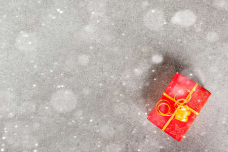 Preparing for the holidays, Christmas background with in a red wrapper with a golden ribbon. Gray background, snow effect, Top view copy spaceの写真素材