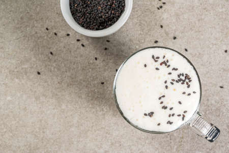 Trendy vegan food recipes, Black Sesame Cappuccino with sesame seeds and whipped coconut milk, grey stone table, copy space top viewの写真素材